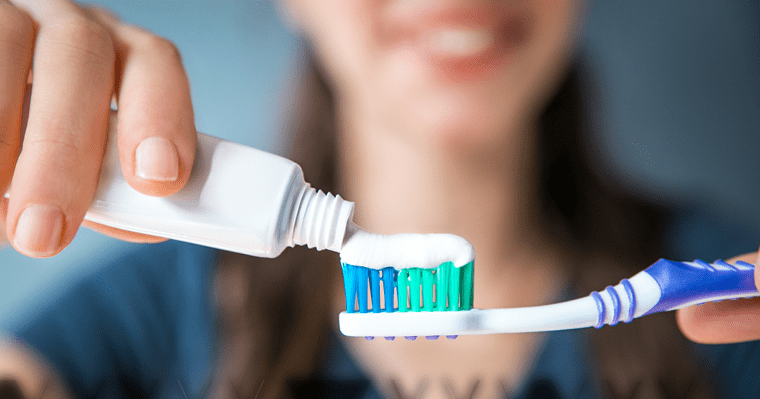 Woman squeezing toothpaste onto a toothbrush.
