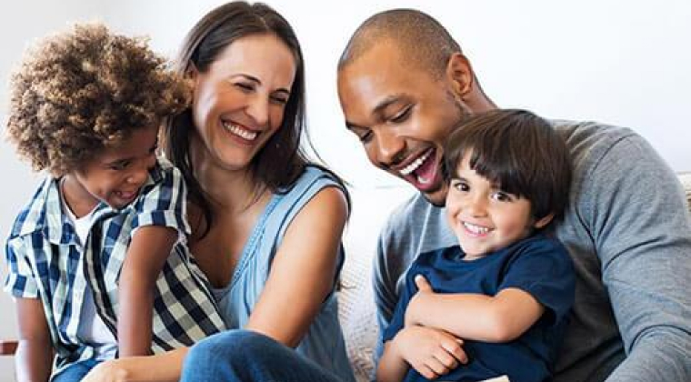 A family smiling on a sofa smiling happily