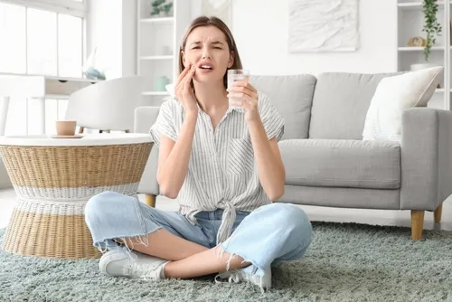 woman experiencing tooth sensitivity while drinking a cold beverage