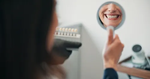 woman checking her smile in a dental mirror