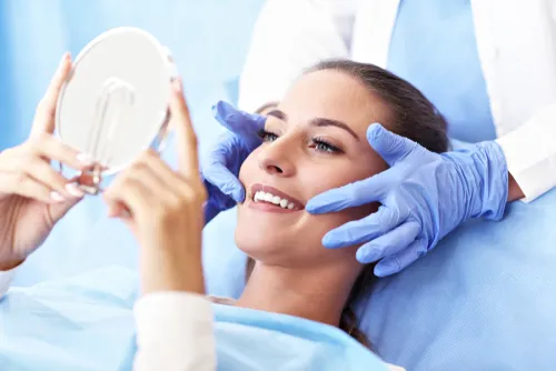 smiling patient checking her teeth in a hand mirror at an Edgewater endodontist visit