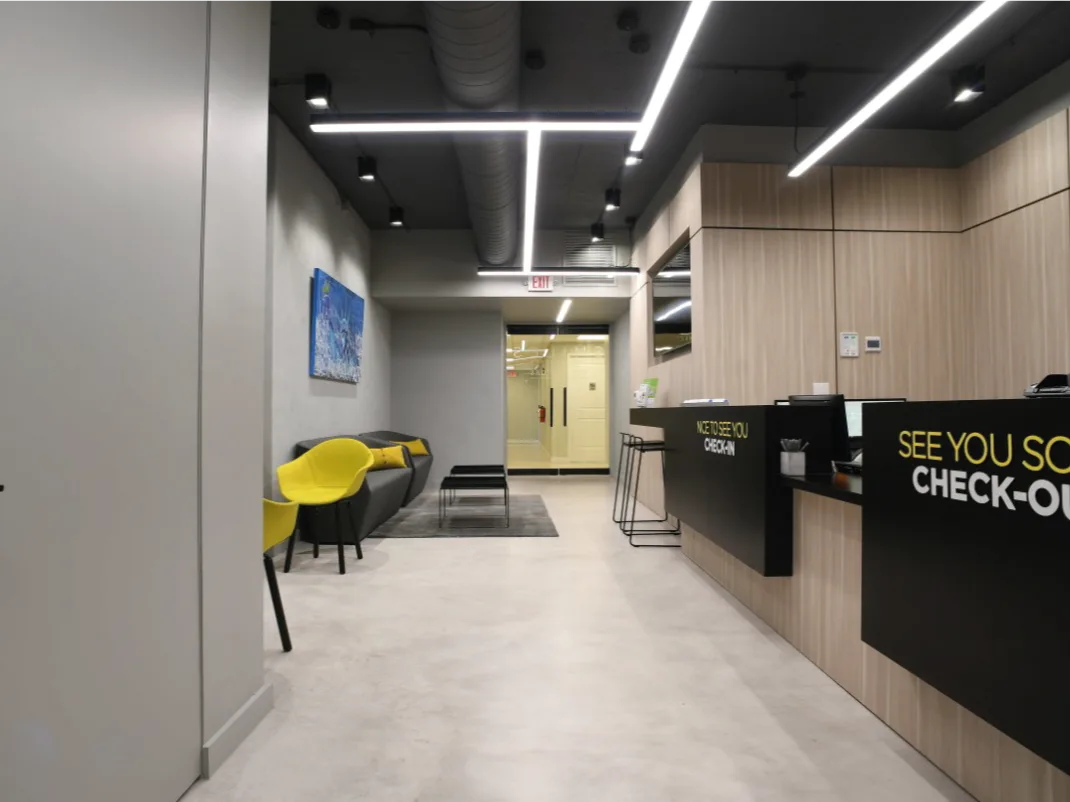 Modern dental office interior with sleek design, reception area, yellow accent chairs, and contemporary artwork.