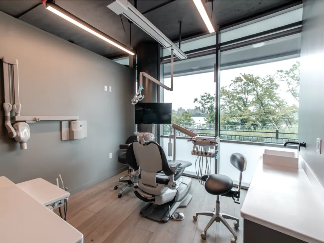 Modern dental office interior with ergonomic dental chair, advanced equipment, and large windows showcasing a river view.