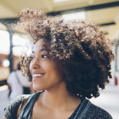 Woman with lots of frizzy hair looking to the side and smiling