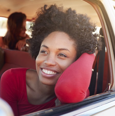 Young woman with a perfect smile leaning out a car window and smiling. 
