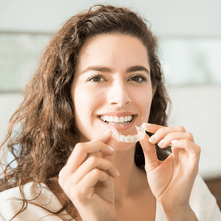 Woman putting an Invisalign aligner in her mouth